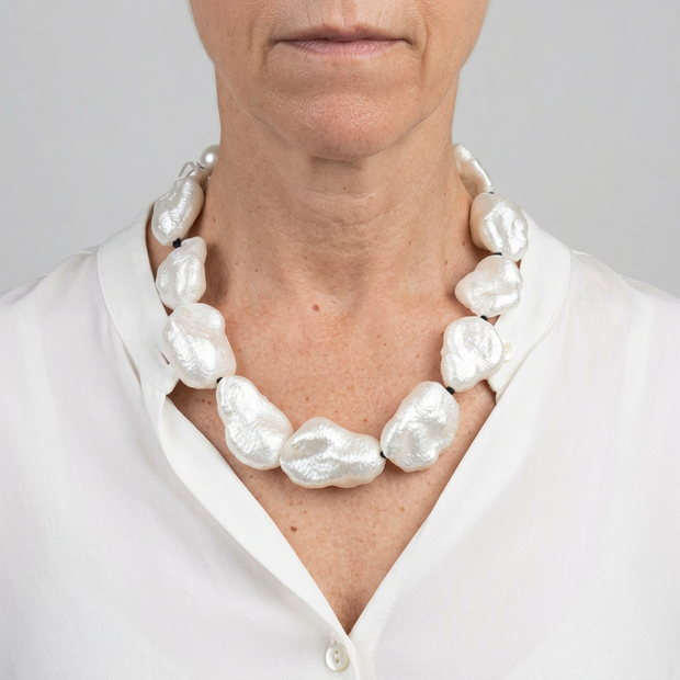 Collar de piezas nacaradas en modelo con blusa blanca y fondo gris claro