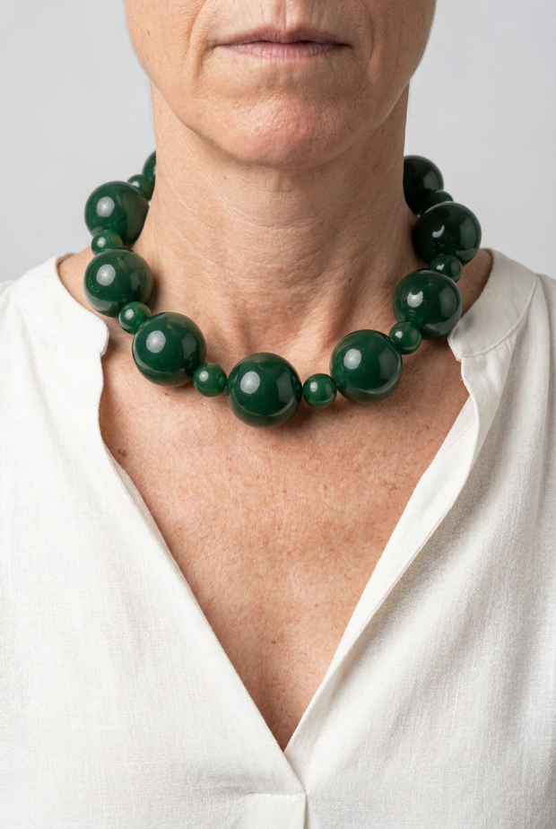 Collar Alternata verde puesto con blusa blanca y fondo neutro