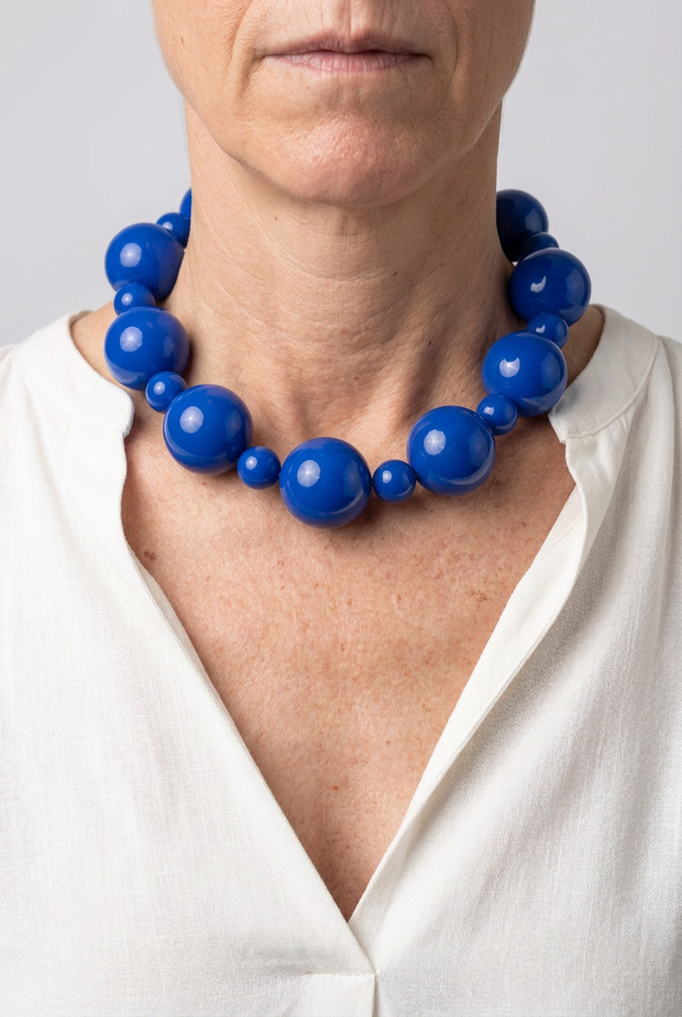 Collar Alternata azul eléctrico puesto con blusa blanca y fondo neutro