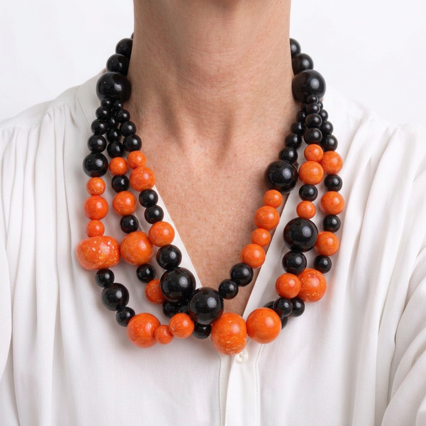 Collar Bacco coral y negro ajustado al cuello sobre modelo con blusa blanca