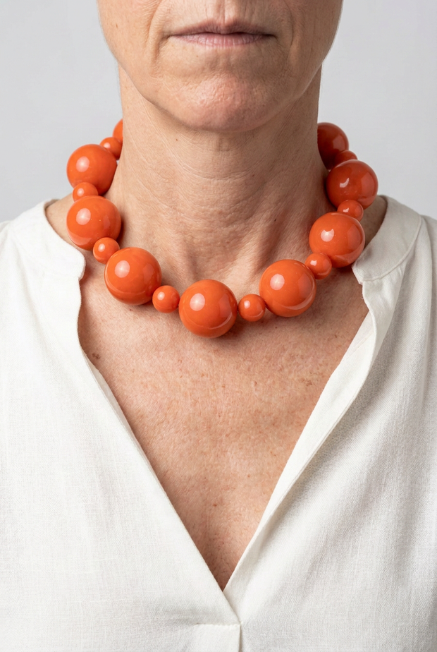 Collar Alternata coral puesto con blusa blanca y fondo neutro