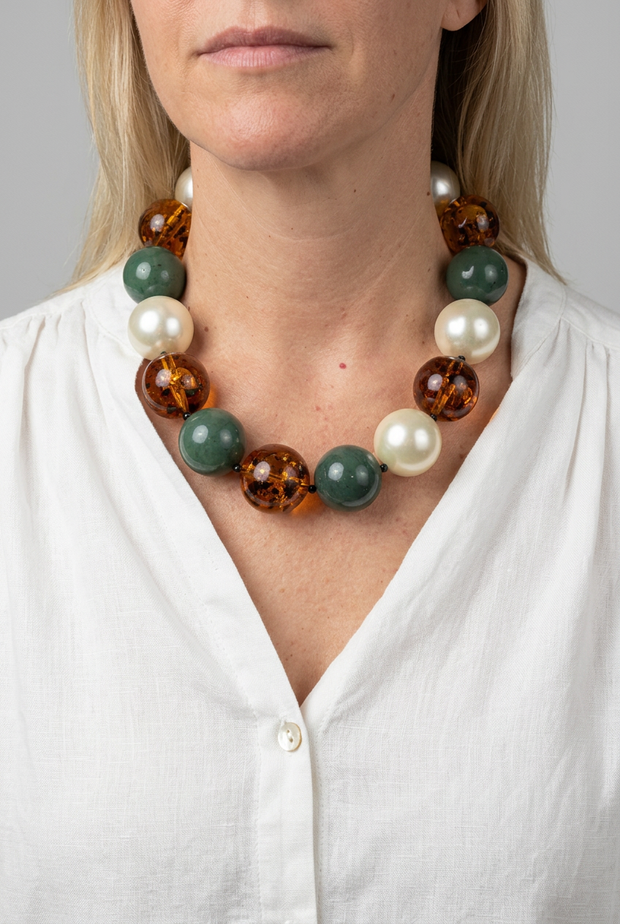Collar Carioca verde y perla puesto, con blusa blanca y fondo neutro