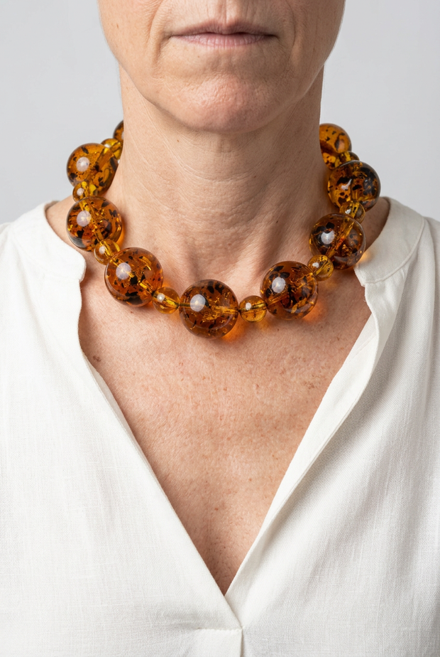 Collar Alternata caramelo puesto con blusa blanca y fondo neutro
