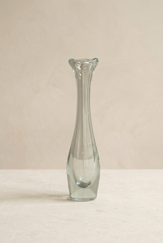 Jarrón de cristal vaselina sin flores sobre piedra clara y pared beige