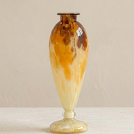 Jarrón ámbar y crema recto sobre piedra clara y pared beige